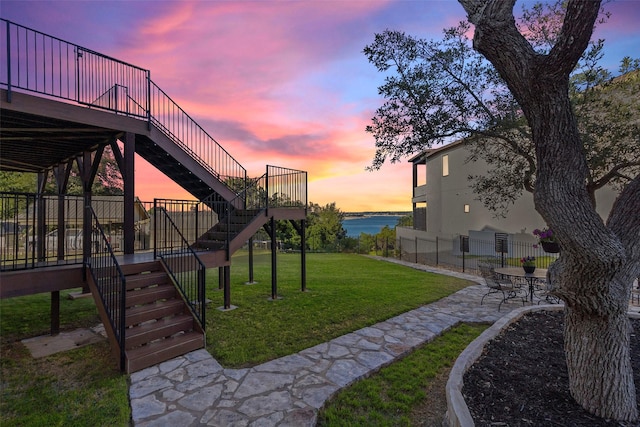 yard at dusk with a patio area and a water view