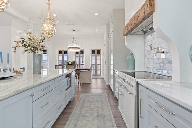 kitchen featuring light stone counters, high end white range, dark hardwood / wood-style floors, premium range hood, and pendant lighting