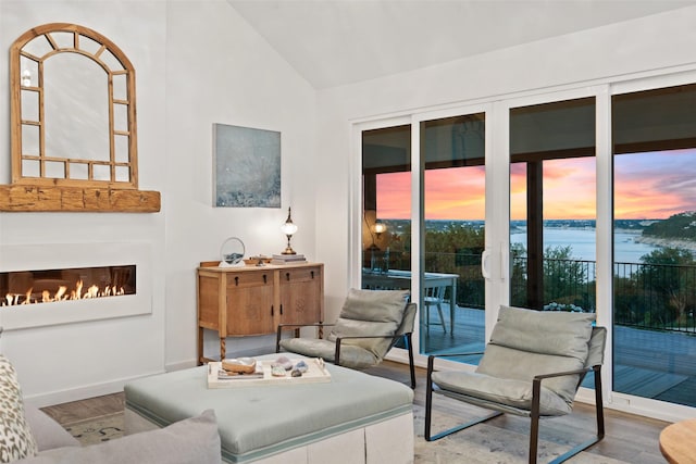 living room with hardwood / wood-style floors, a water view, and lofted ceiling