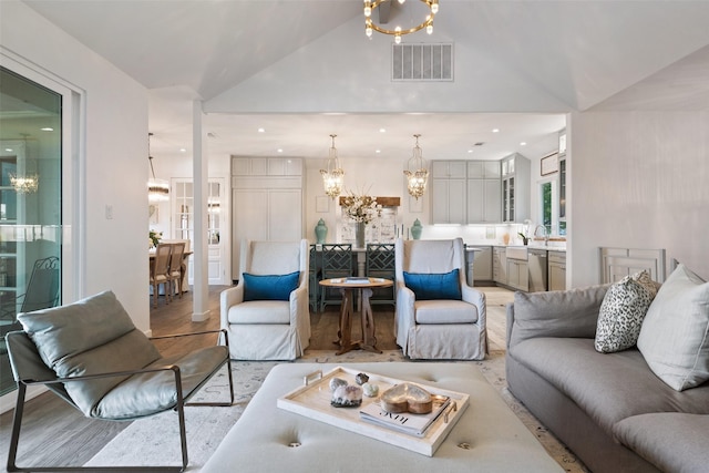 living room featuring light hardwood / wood-style flooring, lofted ceiling, and an inviting chandelier