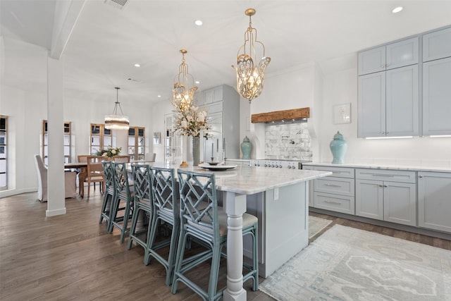 kitchen with a kitchen breakfast bar, light wood-type flooring, a center island with sink, decorative light fixtures, and gray cabinets