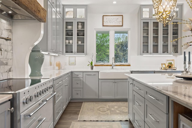 kitchen featuring sink, dark hardwood / wood-style flooring, gray cabinetry, and wall chimney range hood