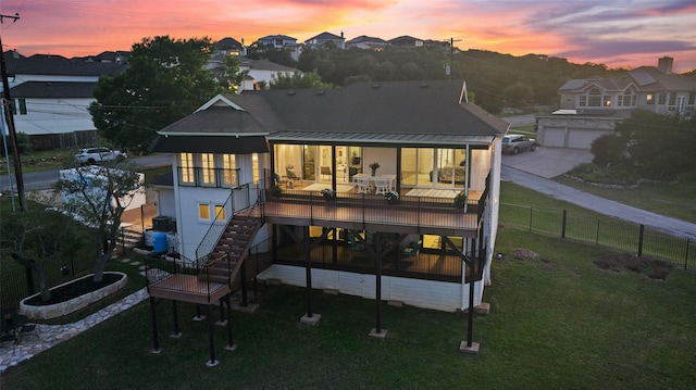 back house at dusk featuring a yard and a garage