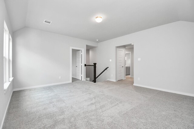 carpeted spare room with vaulted ceiling