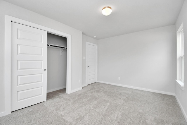 unfurnished bedroom featuring baseboards, carpet flooring, and a closet