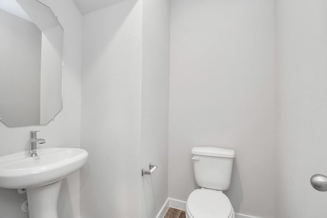 bathroom with hardwood / wood-style floors, toilet, and sink