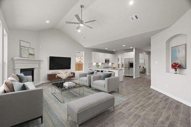 living room with high vaulted ceiling, light hardwood / wood-style flooring, ceiling fan, and sink