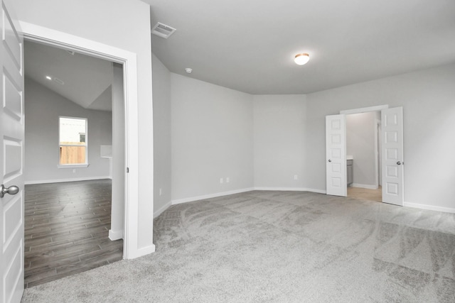 carpeted empty room with vaulted ceiling