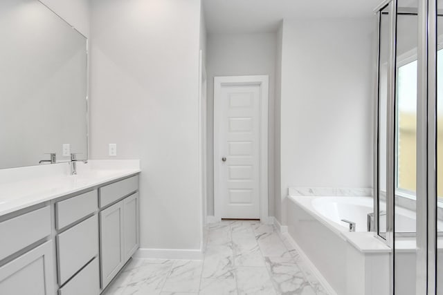 full bath with plenty of natural light, a garden tub, marble finish floor, and baseboards