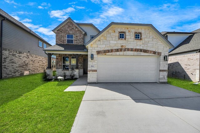 view of front of property featuring a front lawn, driveway, stone siding, covered porch, and an attached garage