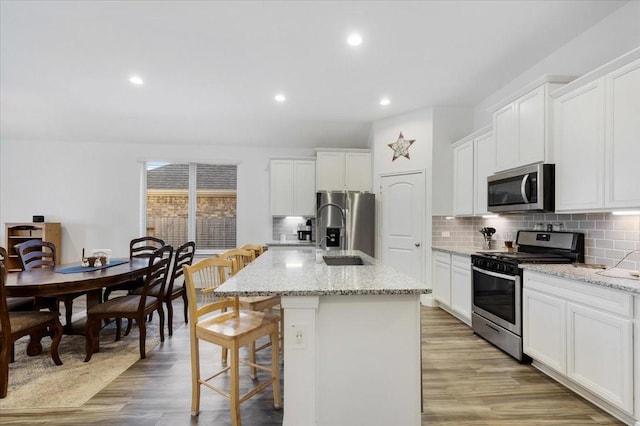 kitchen featuring light hardwood / wood-style floors, stainless steel appliances, and a kitchen island with sink