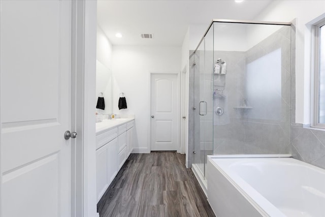 bathroom featuring vanity, plus walk in shower, a healthy amount of sunlight, and hardwood / wood-style flooring