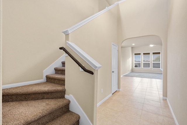 stairway featuring a high ceiling and tile patterned floors