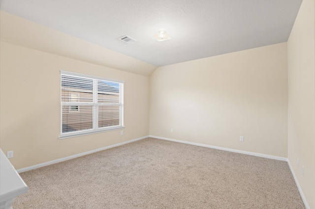 spare room featuring light colored carpet and vaulted ceiling