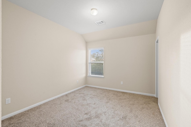 carpeted empty room featuring vaulted ceiling