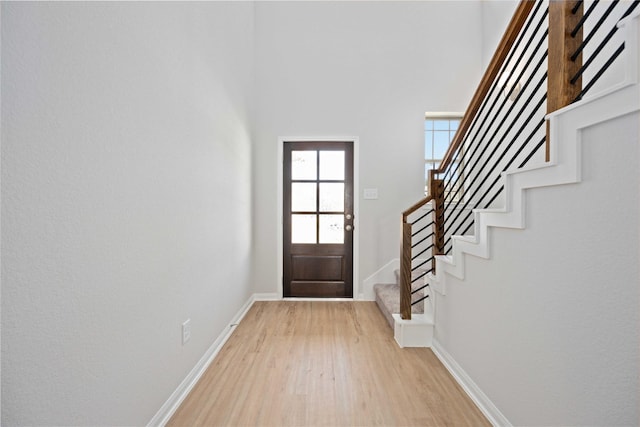 doorway to outside featuring light wood-type flooring and a towering ceiling