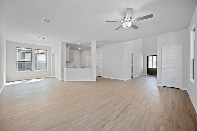 unfurnished living room featuring ceiling fan with notable chandelier and light hardwood / wood-style floors