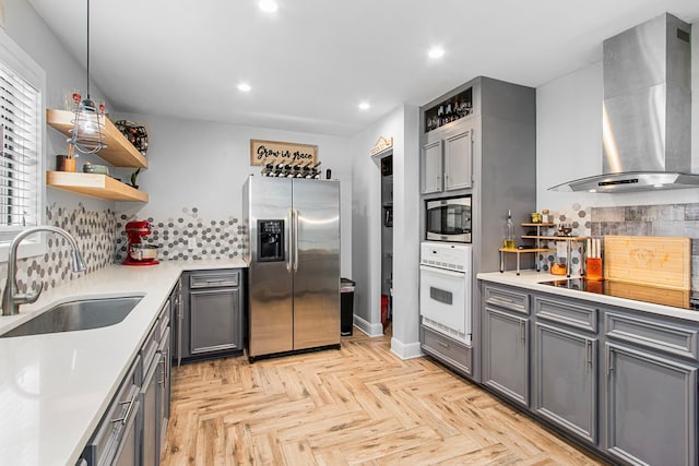 kitchen with gray cabinetry, sink, wall chimney exhaust hood, decorative backsplash, and appliances with stainless steel finishes