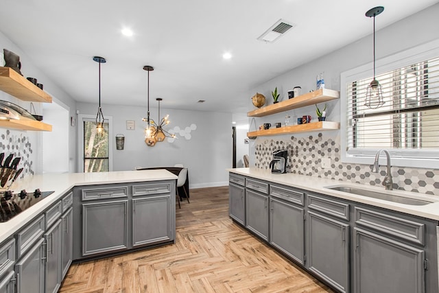 kitchen featuring kitchen peninsula, black electric stovetop, decorative backsplash, sink, and hanging light fixtures