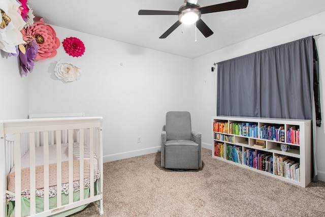 carpeted bedroom with ceiling fan and a nursery area