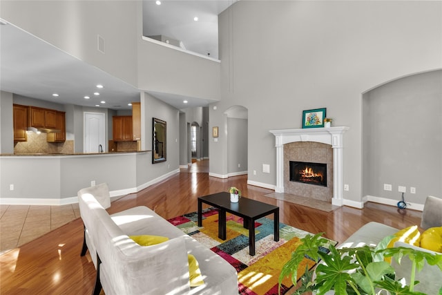 living room with hardwood / wood-style flooring, a fireplace, and a high ceiling