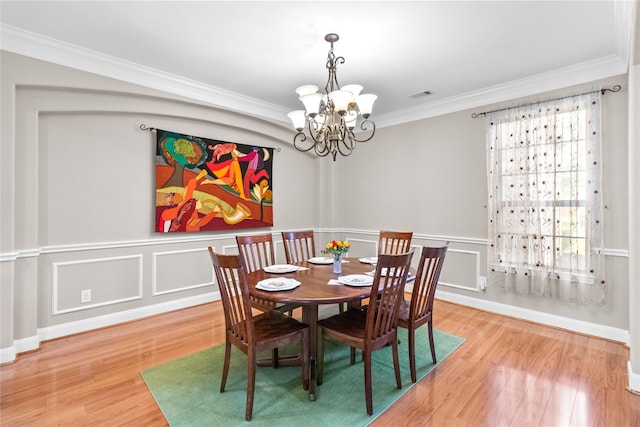 dining area featuring an inviting chandelier, wood-type flooring, and ornamental molding