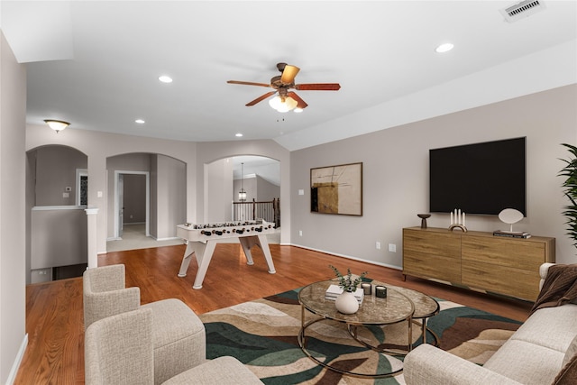 living room with wood-type flooring, ceiling fan with notable chandelier, and lofted ceiling