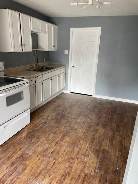 kitchen featuring white range with electric stovetop, white cabinetry, sink, and dark wood-type flooring