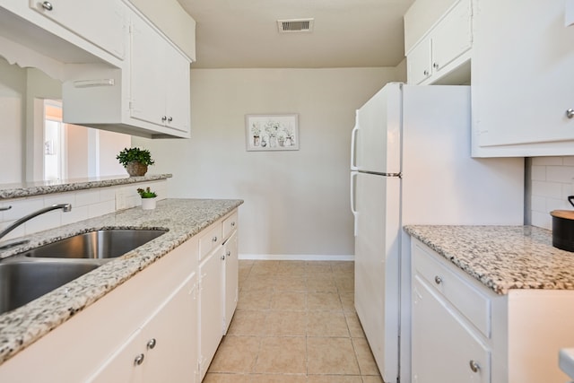 kitchen with white cabinets, white refrigerator, light tile patterned flooring, and sink