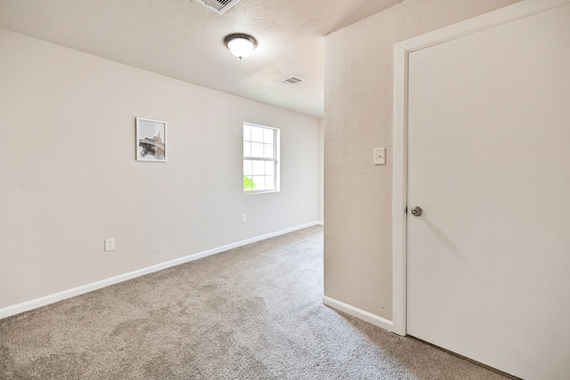 unfurnished room featuring carpet and a textured ceiling