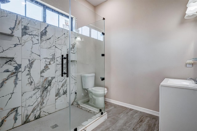 bathroom with hardwood / wood-style floors, vanity, toilet, and a shower with shower door