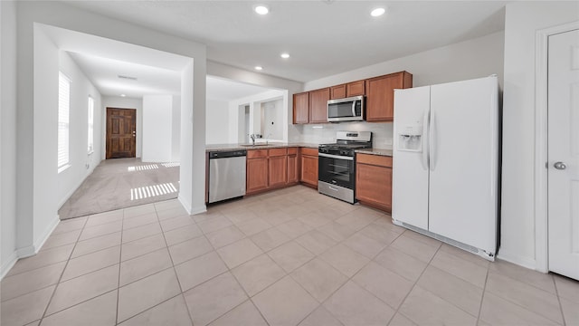 kitchen with decorative backsplash, light tile patterned flooring, sink, and appliances with stainless steel finishes