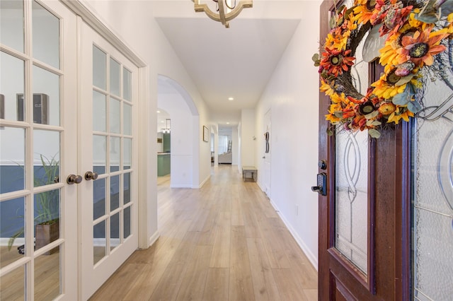 corridor with french doors and light wood-type flooring