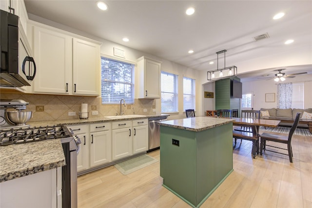 kitchen with white cabinets, sink, light hardwood / wood-style flooring, a kitchen island, and stainless steel appliances