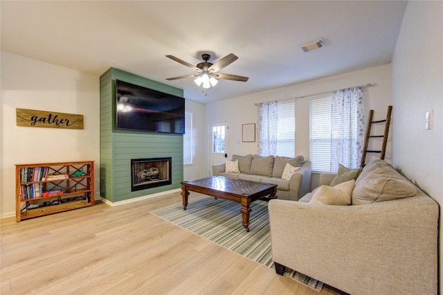 living room with hardwood / wood-style floors, ceiling fan, and a fireplace