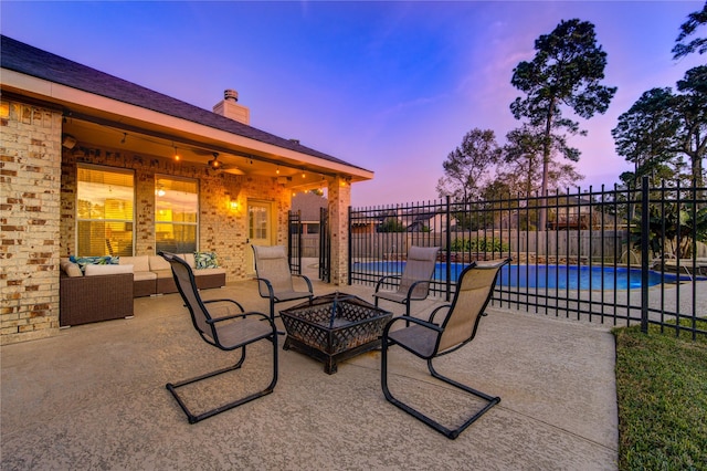 patio terrace at dusk with a fenced in pool, ceiling fan, and an outdoor living space with a fire pit