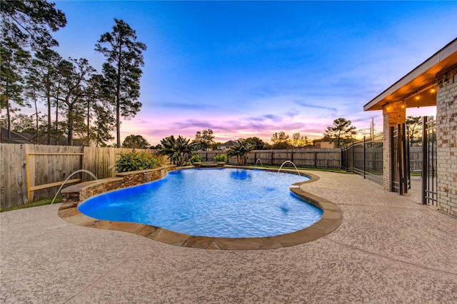 pool at dusk with pool water feature and a patio