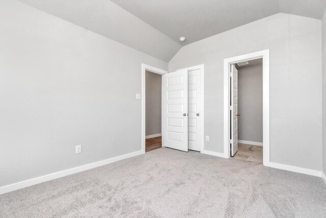 unfurnished bedroom with a closet, light colored carpet, and vaulted ceiling