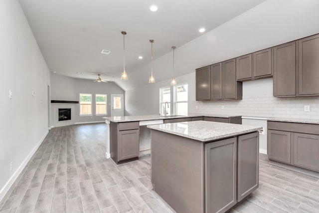 kitchen featuring ceiling fan, sink, tasteful backsplash, pendant lighting, and vaulted ceiling