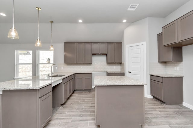 kitchen with sink, pendant lighting, gray cabinets, a kitchen island, and lofted ceiling