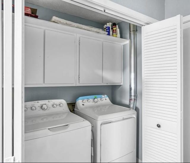 clothes washing area featuring cabinets and independent washer and dryer