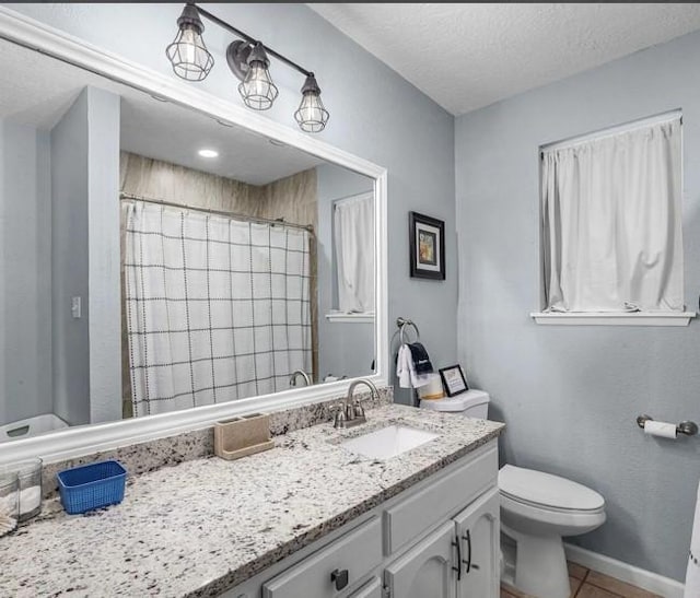 bathroom with vanity, a textured ceiling, tile patterned floors, and toilet