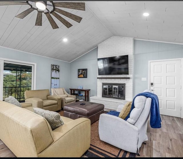 living room featuring ceiling fan, crown molding, a fireplace, light hardwood / wood-style floors, and lofted ceiling