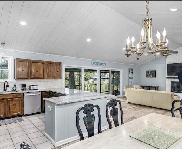 kitchen featuring stainless steel dishwasher, light stone counters, light tile patterned floors, hanging light fixtures, and lofted ceiling