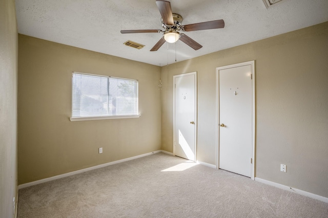 unfurnished bedroom featuring ceiling fan, light colored carpet, and a textured ceiling