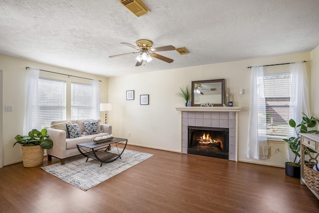 living room with a fireplace, a textured ceiling, a wealth of natural light, and dark wood-type flooring