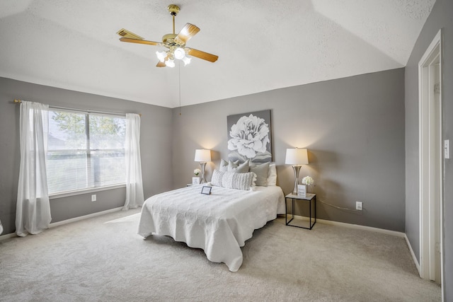 bedroom featuring ceiling fan, light colored carpet, a textured ceiling, and vaulted ceiling