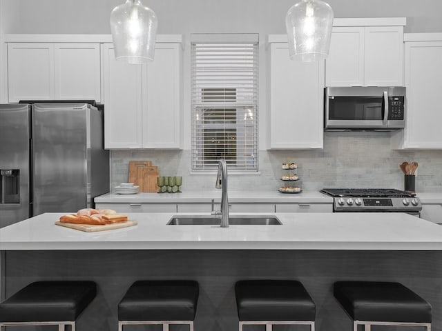 kitchen with pendant lighting, sink, decorative backsplash, white cabinetry, and stainless steel appliances