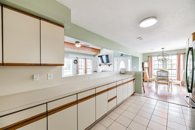 kitchen featuring white cabinets, decorative light fixtures, ceiling fan with notable chandelier, and a wealth of natural light