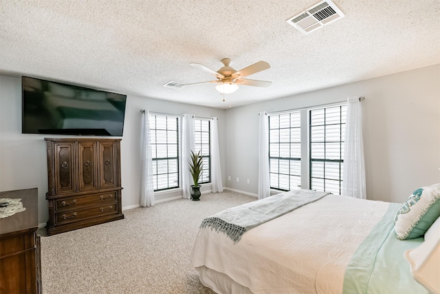 bedroom featuring ceiling fan, light carpet, and a textured ceiling